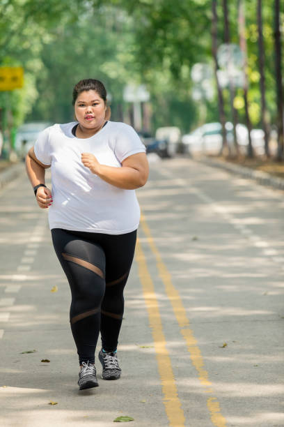 istock Fat woman jogging on the road 1035312474