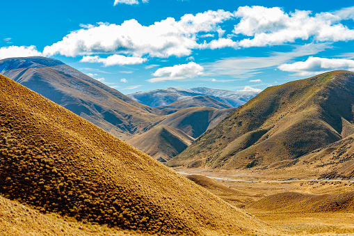 Road passing through beautiful color and texture of mountains and valleys which start to be covered with snow, while other are green and turning golden brown.