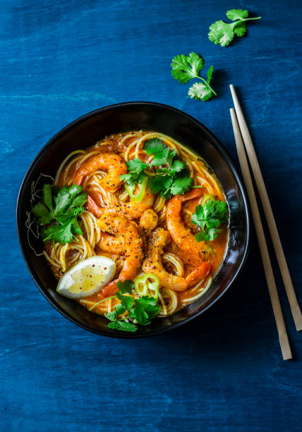 sopa de laksa coco camarão sobre um fundo azul, vista superior. copie o espaço. comida de estilo asiático - coriander seed cilantro seed ingredient - fotografias e filmes do acervo