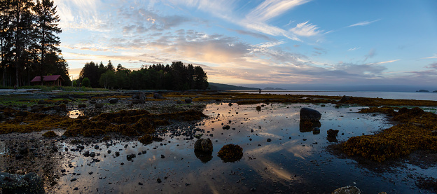 Beautiful panoramic view of a rocky beach during a vibrant cloudy summer sunset.Taken in Port Hardy, Northern Vancouver Island, BC, Canada.