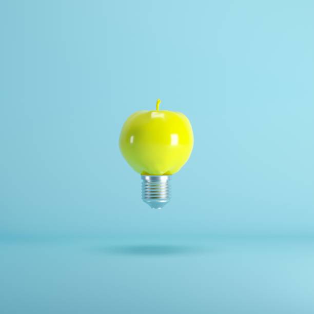 istock Yellow Apple Lightbulb floating on blue background. minimal idea concept. 1035362220