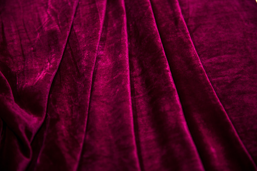 Red velvet fabric folded in an accordion, lies on the table top view, background on all the photo
