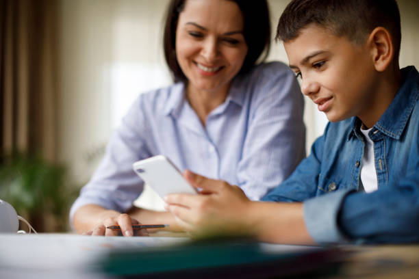mother and son using mobile phone for homework - homework teenager mobile phone school imagens e fotografias de stock