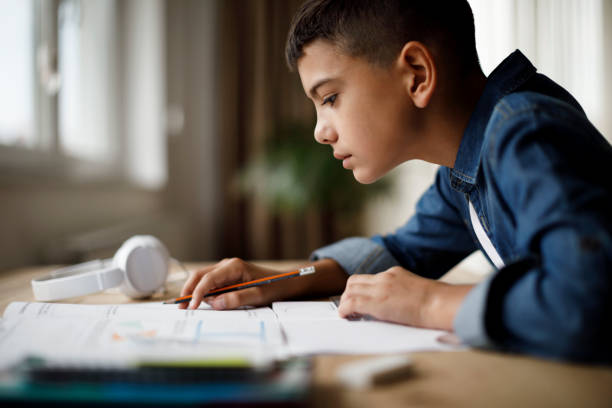 jeune garçon en train de faire ses devoirs - livre dexercice photos et images de collection