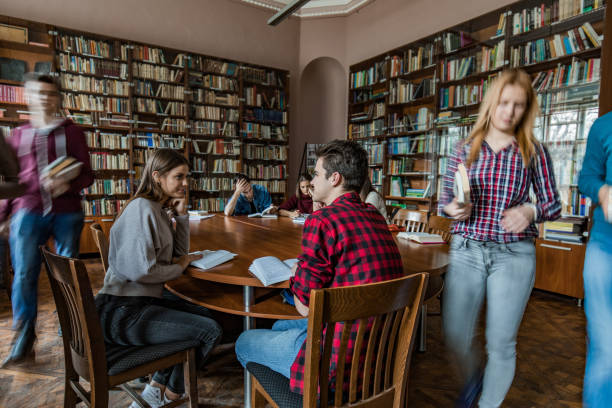 istock High school couple sitting in the library and communicating. 1035400638