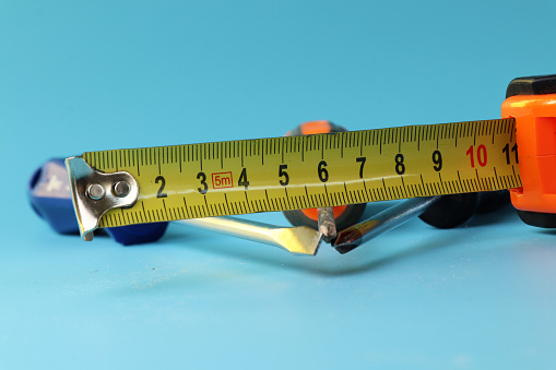 A tape measure with screwdrivers, cross-point screwdriver. All is on blue background