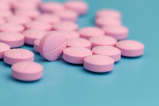 pink pills on blue background, selective focus, medical and health care concept