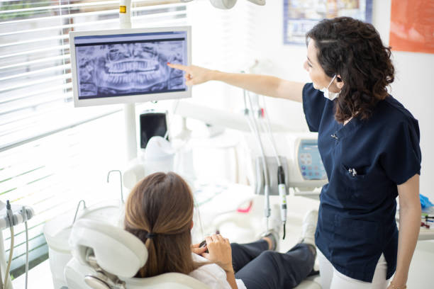 Female dentist talking to her patient at dentist's office stock photo