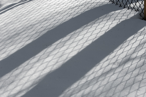 Winter landscape. texture background. reflection of shadows on the snow from the artificial fence