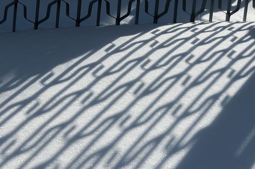 Winter landscape. Textural background. reflection of shadows on the snow with an artificial fence. shadow and light. Landscape City