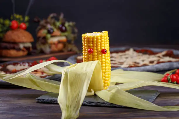 Yellow corn monster with red eyes. Funny healthy snack. Halloween party.