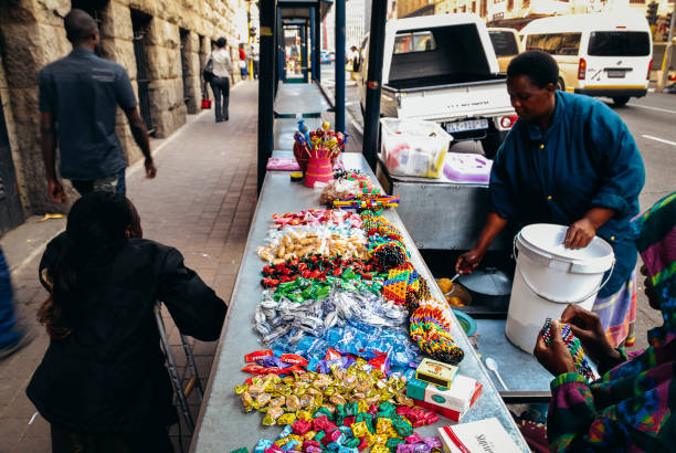 Johannesburg , Gauteng / South Africa -september 11 2018 :woman on crutches waiting for a lady to finish cooking fat cake at a street stall midday Johannesburg cbd