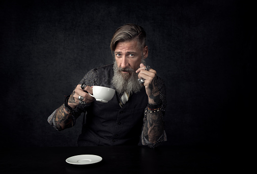 Portrait of a bearded man with a cup of coffee. Isolated on a black background