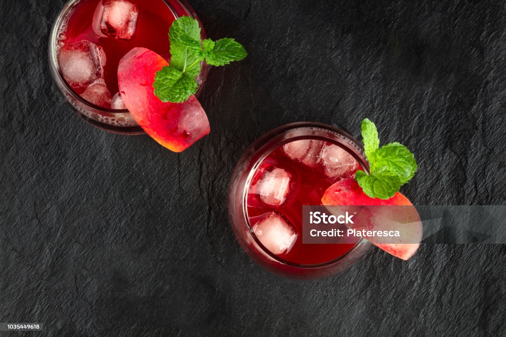 Overhead photo of vibrant red drinks with mint on black An overhead photo of two vibrant red drinks with peaches and mint on black Above Stock Photo