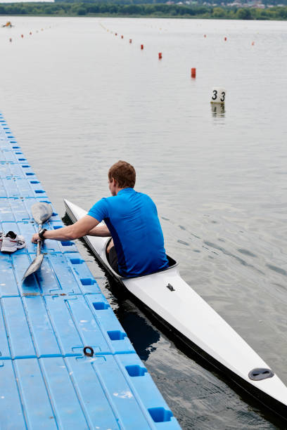 Rear view of young kayaker sitting in kayak preparing for competition
