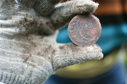 Aged 5 kopeks coin of Russian empire in the hand of coin finder. Treasure hunting concept. In search of a lost treasure.
