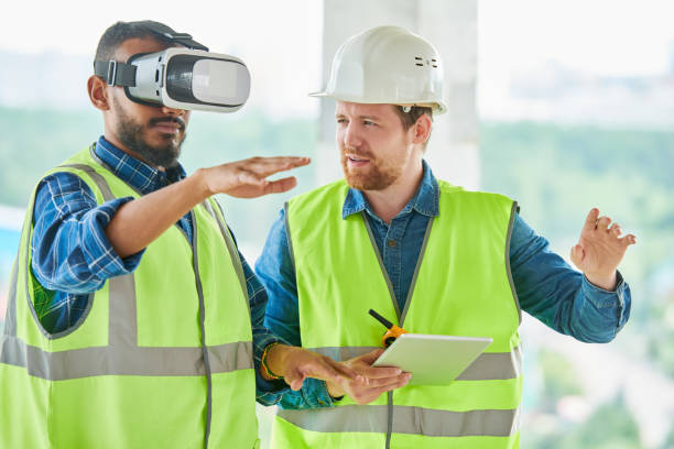 Using VR simulator for building visualization Concentrated handsome mixed race engineer with beard gesturing while using VR simulator for building visualization, his colleague explaining project to him training equipment stock pictures, royalty-free photos & images