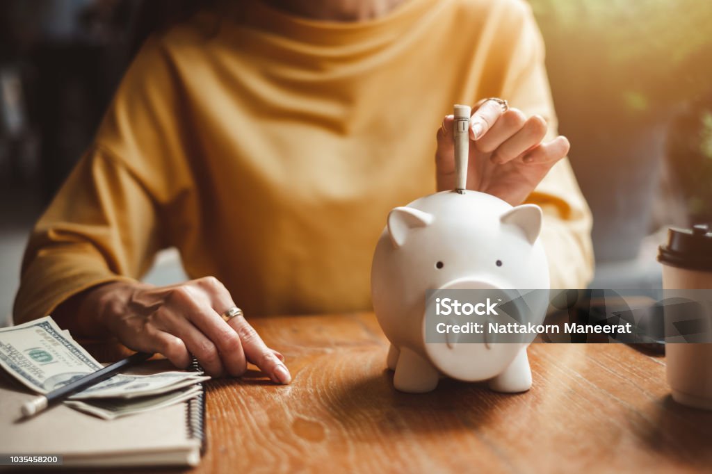 woman hand putting money bank note dollar into piggy for saving money wealth and financial concept. Savings Stock Photo