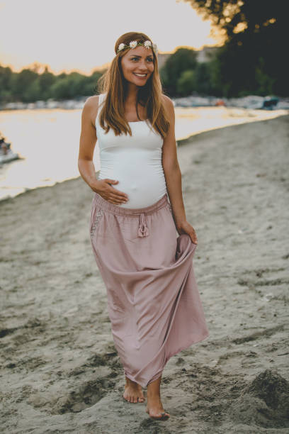 istock Young pregnant woman walking by the river 1035458218