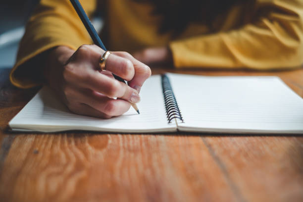 Close up woman hand writing on notebook Close up woman hand writing on notebook note stock pictures, royalty-free photos & images