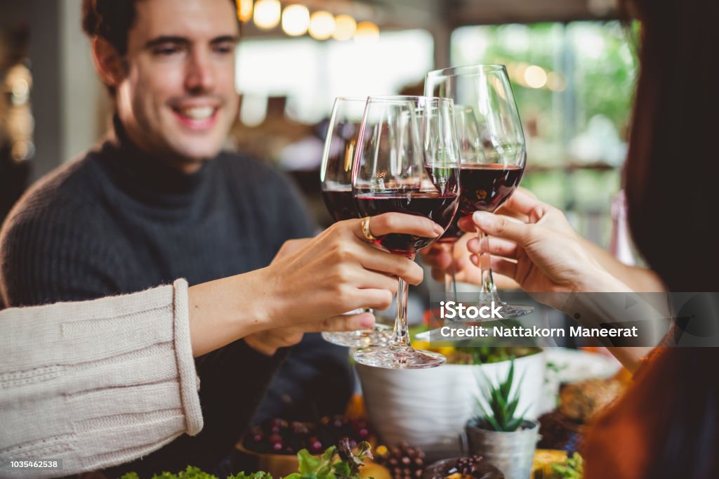 Group of young people celebrating Christmas party dinner with clinking glass of wine Wine Stock Photo