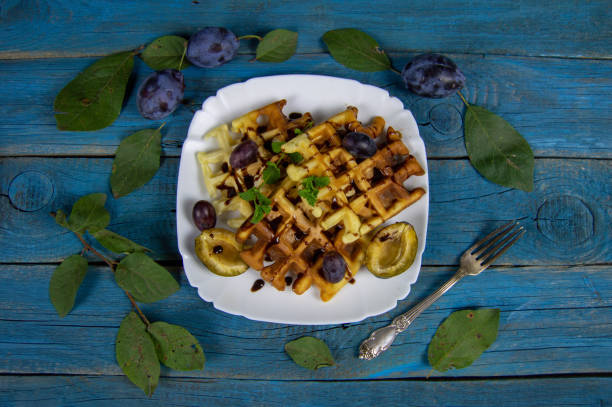 Fresh Belgian wafers with chocolate sauce and plums. Delicious summer breakfast stock photo