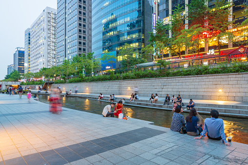 Seoul, South Korea - June 16, 2017: People are sitting and relaxing at Cheonggyecheon water Stream, Cheonggyecheon is 10.9 km long, modern public recreation space in downtown of Seoul, South Korea.