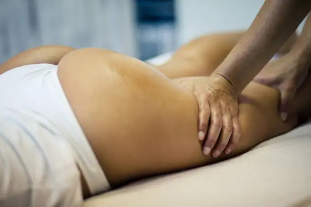 Beautiful body. The masseur makes Anti-cellulite massage on the buttock and thighs of the patient. Close up.