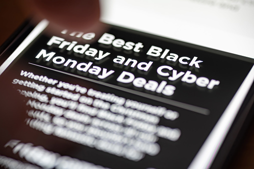 Human finger thumb over Black Friday and Cyber Monday Deals text on shopping app on smartphone screen closeup.