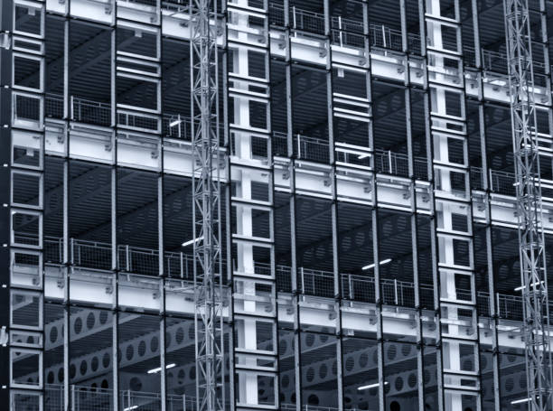 istock monochrome blue tinted view of a large building development under construction with steel framework and girders supporting the metal floors with safety fences and hoists 1035487722