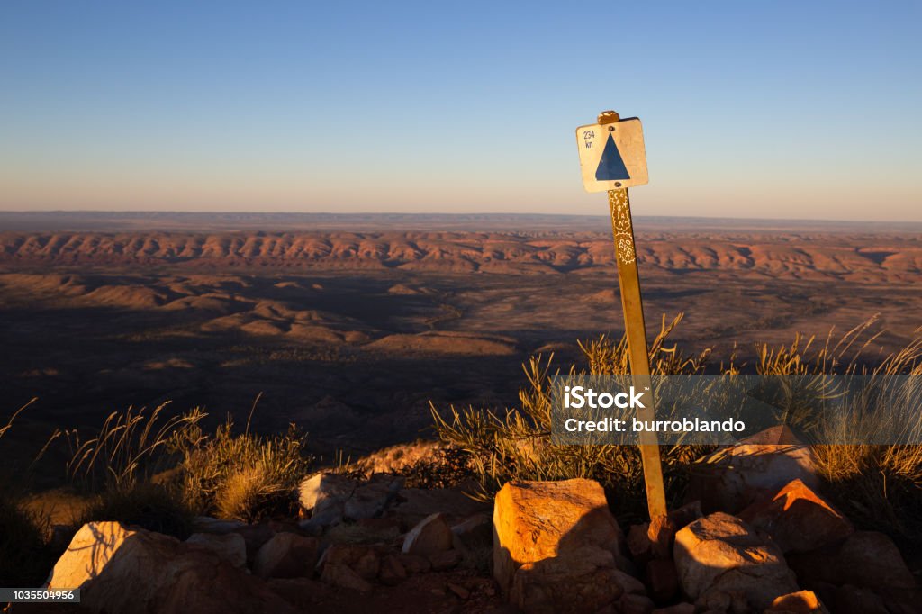 A sign at the top of Mount Sonder shows the kilometres back to Alice Springs The amazing colours of a beautiful sunset as seen from the peak of Mount Sonder in the middle of winter Larapinta Trail Stock Photo