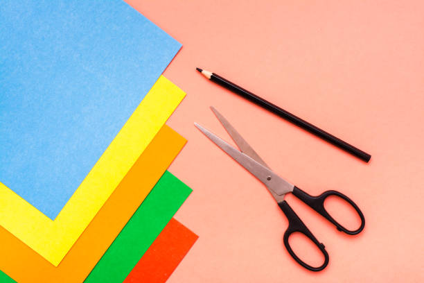 istock Sheets of colored cardboard, scissors and pencil on a red background. 1035505096