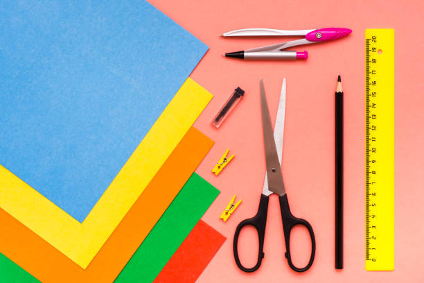 istock Items for creativity - sheets of colored cardboard, scissors, compasses, pencil and ruler on a red background 1035505112