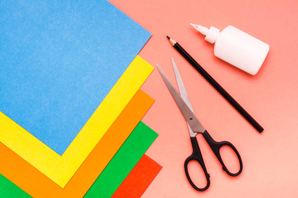 istock Items for creativity - sheets of colored cardboard, scissors, pencil and glue on a red background 1035505114