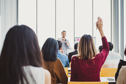 Back view business woman raising hand for asking speaker for question and answer concept in meeting room for seminar