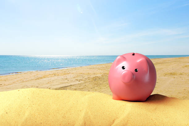 istock Piggy bank on a beach. Vacation savings concept 1035512436