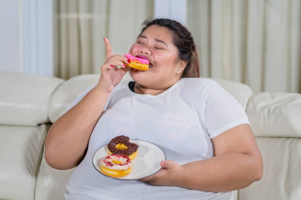 istock Overweight woman eating doughnuts with pleasure 1035518596