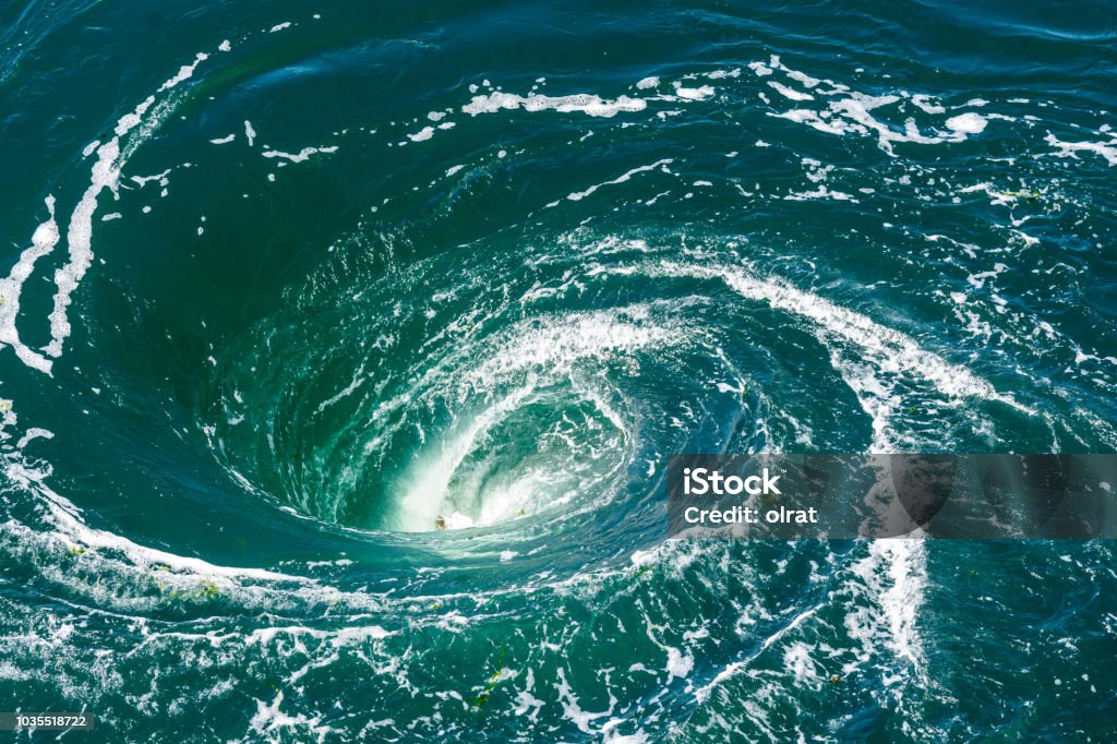 A powerful whirlpool is generated at the surface of the green waters of the river Rance by the action of a turbine of the tidal power station near Saint-Malo in Brittany, France. Whirlpool Stock Photo
