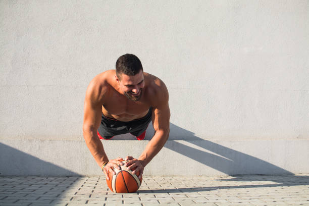 muscular build man doing push ups on basketball outdoors - exercising men push ups muscular build imagens e fotografias de stock