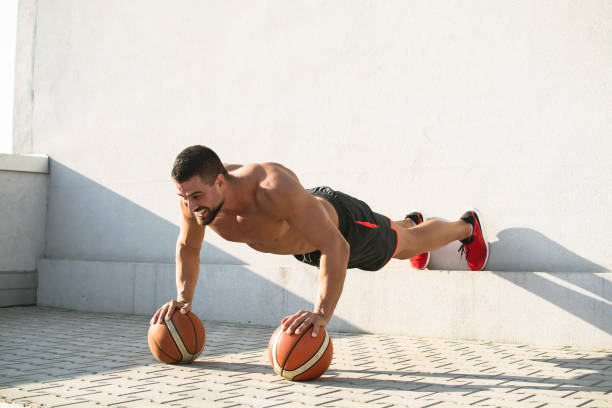 muscular build man doing push ups on basketball outdoors - exercising men push ups muscular build imagens e fotografias de stock