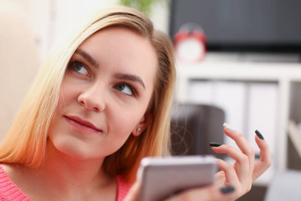 istock young pretty blond womansit on sofa hold smartphone in hands 1035534620