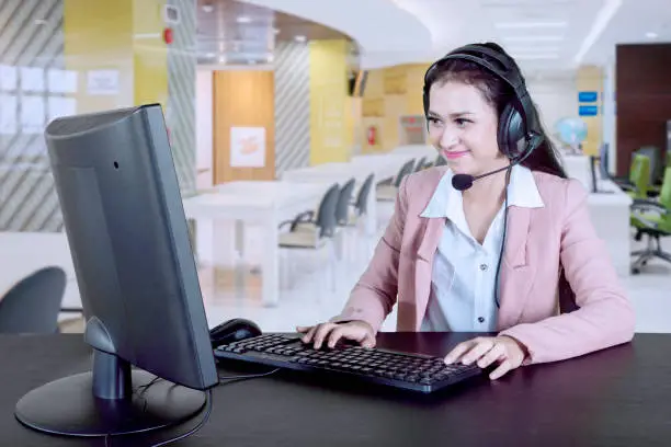Beautiful and friendly customer service with headset using computer