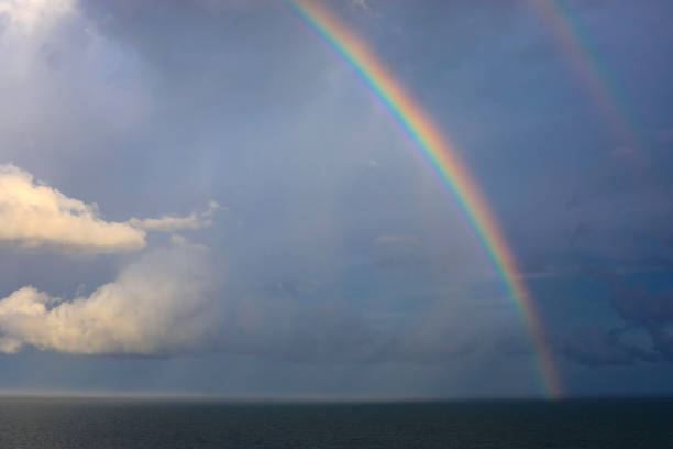 istock Bright two rainbow in the sky with clouds above the sea.Thailand 1035541284