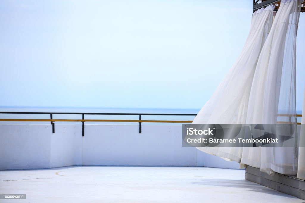 The view in to the balcony of rooftop background the ocean. House of the sea. wind blow the curtain Curtain Stock Photo