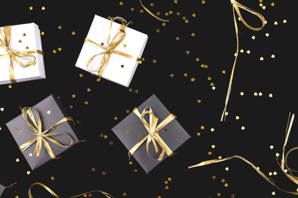 istock Black and white gift boxes with gold ribbon on shine background. 1035544018