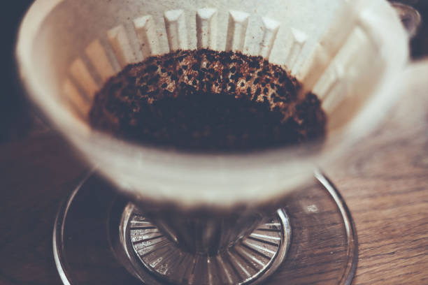 istock coffee brewing method.barista pouring hot water on rough brown bubbles coffee through drip filter, home brewing process on table bar drip.Thailand. ground coffee beans contained in a filter. 1035544800