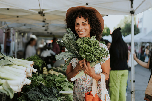 Hermosa mujer compra kale en un mercado photo