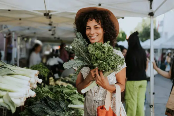 Photo of Beautiful woman buying kale at a farmers market