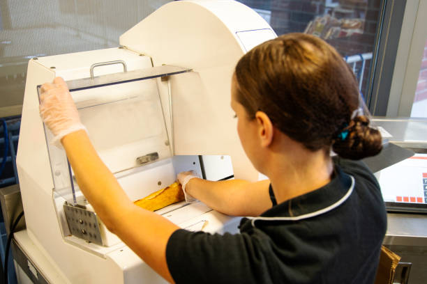 istock Female employee in a supermarket using a bread slicing machine 1035545288