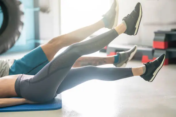 Unrecognizable, young heterosexual couple doing core workout at the gym.